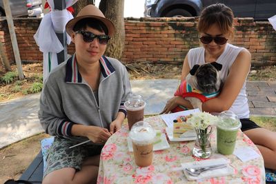 Portrait of women sitting with dog at caf�