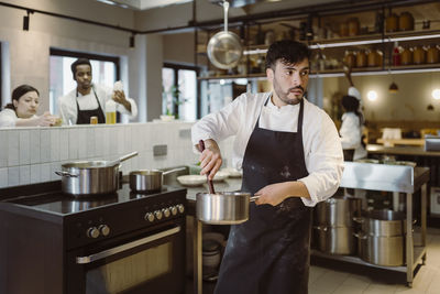 Male chef stirring while standing in commercial kitchen at restaurant