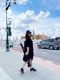 Full length side view of man standing in city against sky