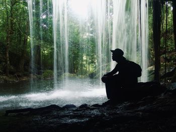 Man sitting on rock in forest