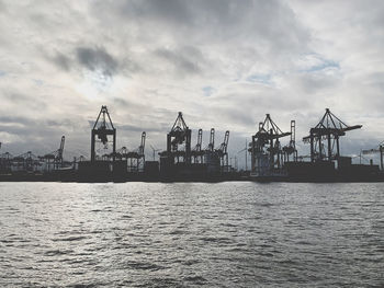 Cranes at commercial dock against sky