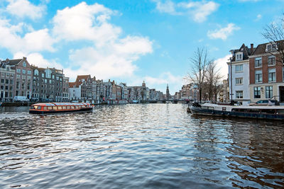 Boats in canal amidst buildings in city against sky