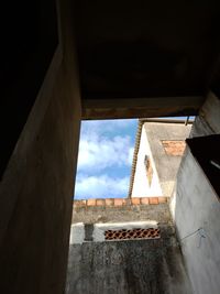 Low angle view of building against sky seen through window