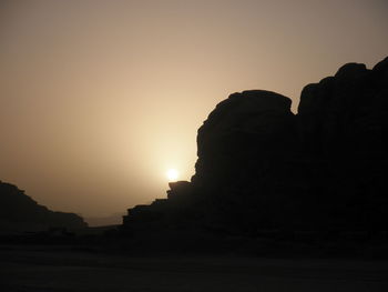 Silhouette rock formation against clear sky during sunset