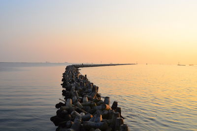 Stack of pebbles on shore against sky during sunset