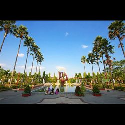 People by palm trees against sky