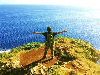 Rear view of man standing by sea against sky