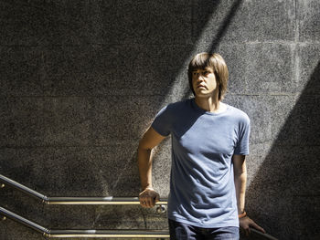 Man in underground pedestrian crossing. man with long hair stands in sunlight on grey stone.