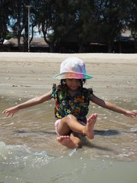 Full length of girl enjoying in water on shore at beach