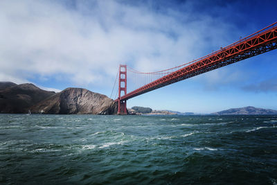 Golden gate bridge over bay against cloudy sky