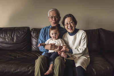 Grandfather and grandmother holding granddaughter and smiling