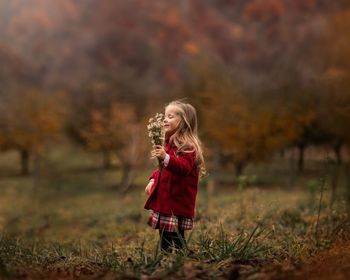 Girl holding umbrella standing on field during autumn