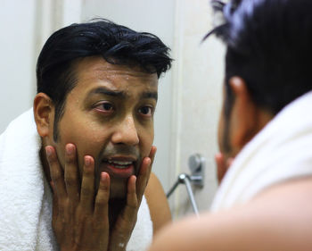 Close-up of wet man looking his reflection in mirror at bathroom