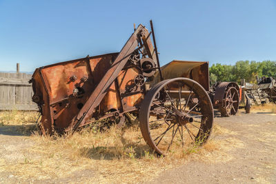 Old rusty bicycle on field against clear sky