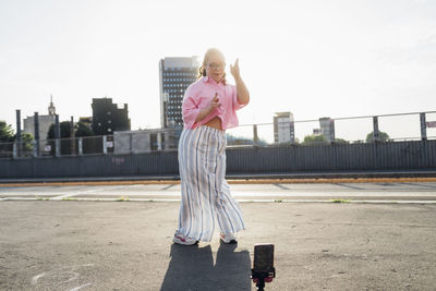 Teenage girl with down syndrome recording dancing video through smart phone on street