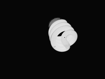 Low angle view of illuminated light bulb against black background