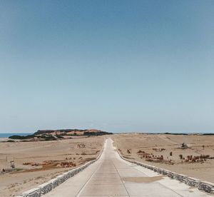 Road amidst desert against clear sky