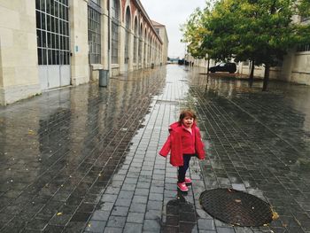 Full length of woman standing on wet road in rainy season