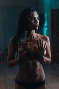 Seductive shirtless woman standing by glass