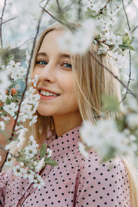 Blonde girl on a spring walk in the garden with cherry blossoms. female portrait, close-up. 