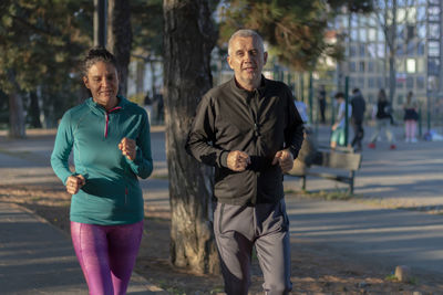 Happy mature couple running and exercising in a park outdoors