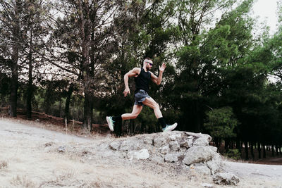 Male sportsperson running on rock against forest