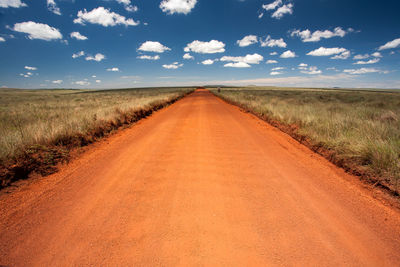 Road amidst field against sky