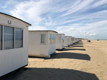 Beach huts by buildings against sky