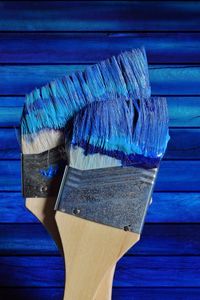 Close-up of paintbrush against blue wall