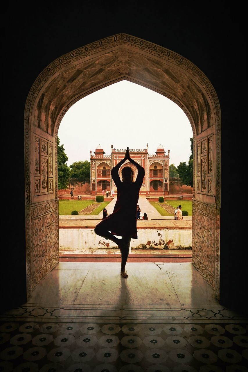 arch, architecture, full length, built structure, indoors, lifestyles, leisure activity, archway, standing, person, clear sky, building exterior, rear view, walking, casual clothing, young women, young adult, tunnel