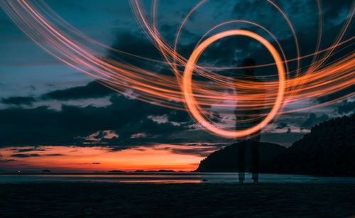 Man standing by light painting at beach during sunset