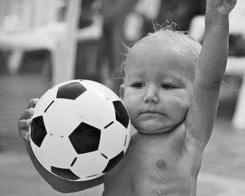 Cute shirtless toddler girl holding soccer ball