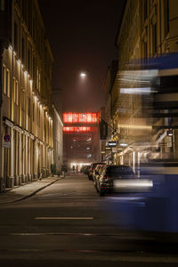 Illuminated road amidst buildings in city at night