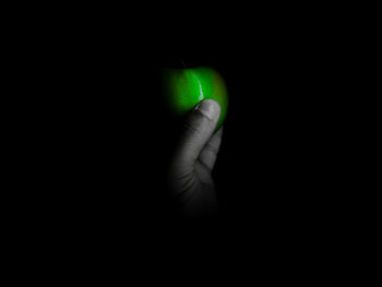 Close-up of hand holding illuminated light over black background