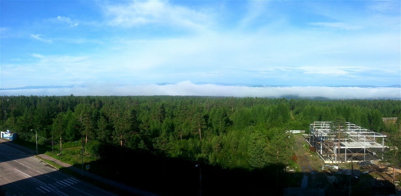 tree, sky, cloud - sky, high angle view, tranquil scene, tranquility, scenics, beauty in nature, town, building exterior, travel destinations, blue, nature, day, growth, tourism, non-urban scene, mountain, wide, green color, outdoors, majestic, wide shot, no people, tourist resort, vacations