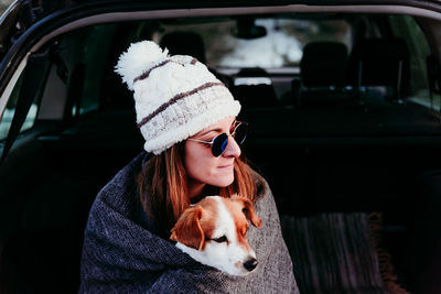 Close-up of woman with dog sitting in car trunk