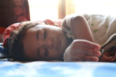 Close-up portrait of girl lying on bed at home