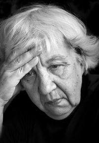 Sad senior woman against black background