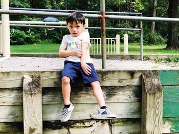 Full length of boy sitting on wood