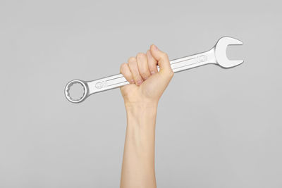 Cropped image of hand holding key against white background