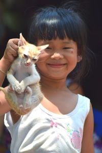 Portrait of smiling cute girl holding cat
