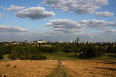 Grassy landscape against cloudy sky at primrose hill