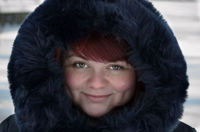 Close-up portrait of smiling young woman wearing fur coat