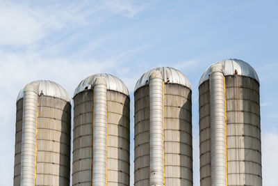 Low angle view of silos against sky