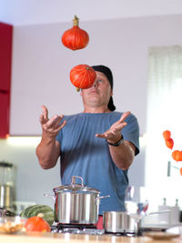 Man playing with pumpkins while preparing food in kitchen