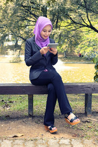 Full length of woman sitting on bench in park