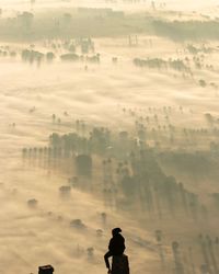 Man sitting on mountain against landscape