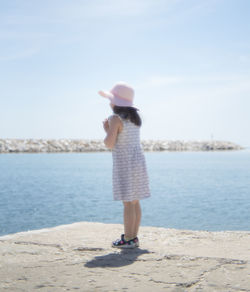 Full length rear view of young woman standing on beach