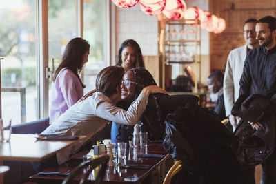 Smiling woman greeting male friend during party at bar