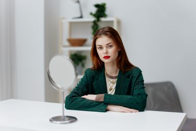 Portrait of young woman using mobile phone while sitting on table